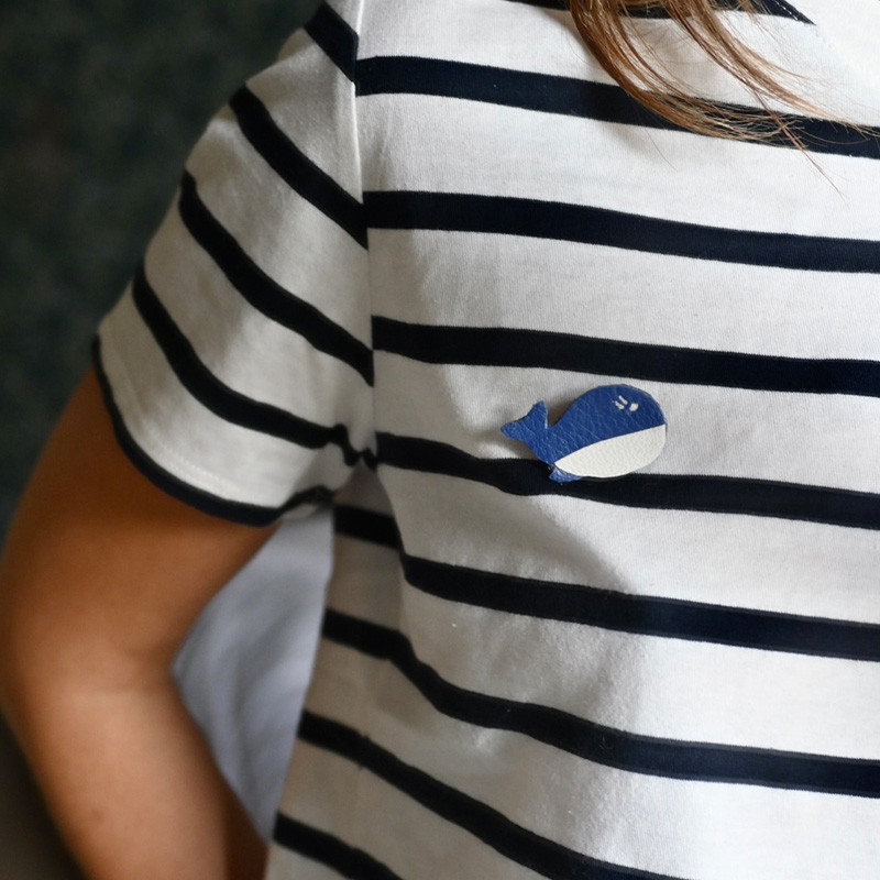 broche en cuir en forme de baleine portée sur un teeshirt marinière