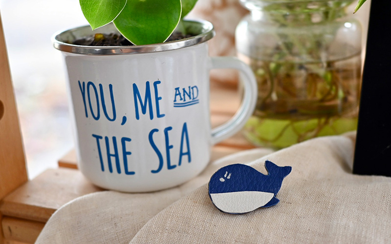 broche en cuir en forme de baleine à côté d'une plante dans un pot